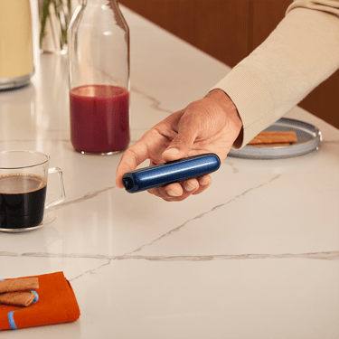 Hand holding a Ploom AURA device with a Navy Blue front panel accessory