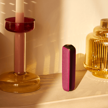 جهاز Ploom AURA باللون الأوركيد الداكن، واقف على طاولة.