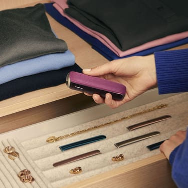 مستخدم يسحب جهاز Ploom AURA باللون الأوركيد الداكن من درج.