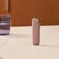 جهاز Ploom مع غطاء خلفي باللون الذهبي الوردي، واقف على طاولة.