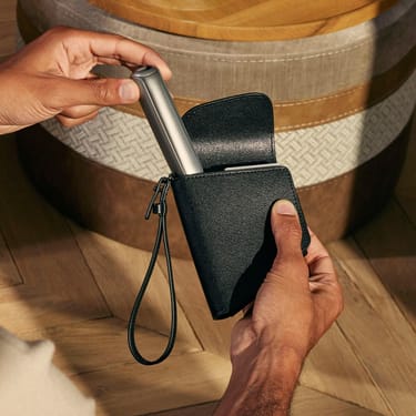 يد تخرج جهاز Ploom AURA من حقيبة Ploom Duo باللون الأسود الداكن.