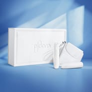 Lateral view of the Ploom AURA Glacier White Collection box with device, back cover and solo carry case.
